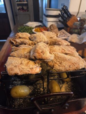Dry rubbed and marinated chicken in roasting rack with potatoes below
